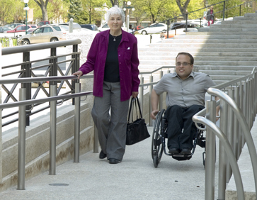 Une personne marchant à côté d’une personne en fauteuil roulant.